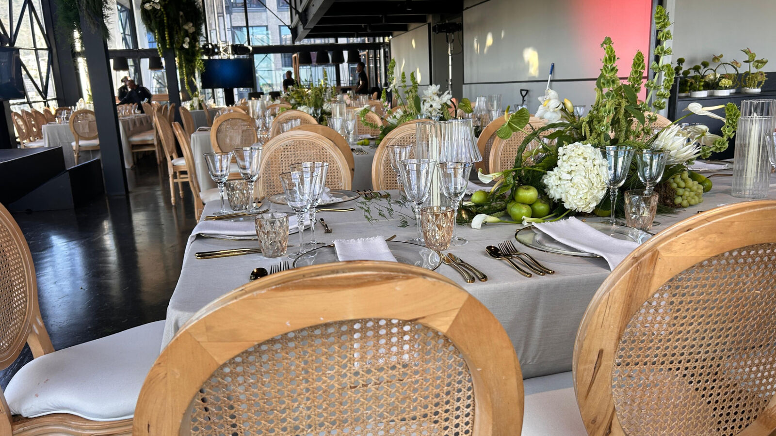 Banquet tables with cane chairs, crystal glassware and gold cutlery