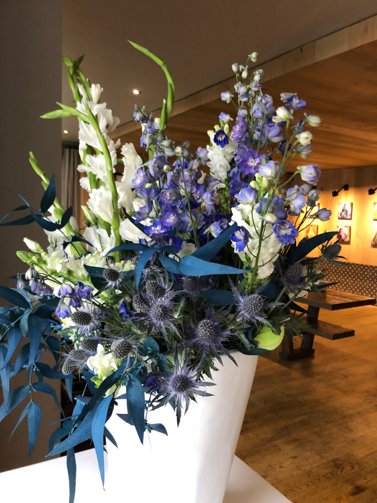Tall blue and white floral arrangement in a white plinth vase